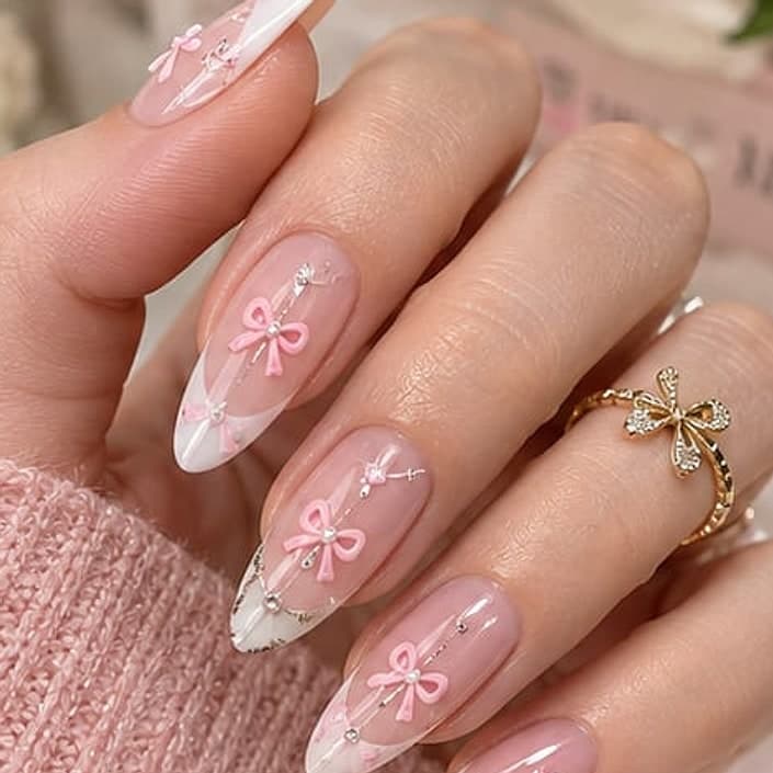 Almond French tip nails with pink coquette bows, tiny gems and a gold bow ring
