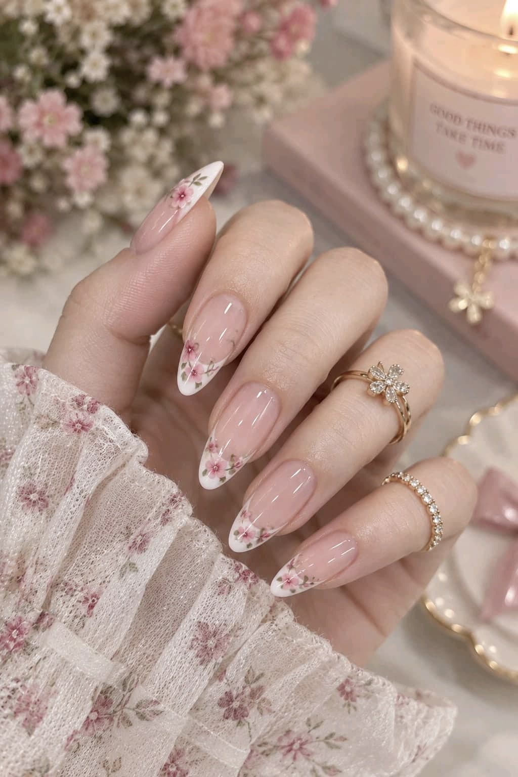 Almond nails with white French tips and tiny hand-painted pink flowers and green leaves