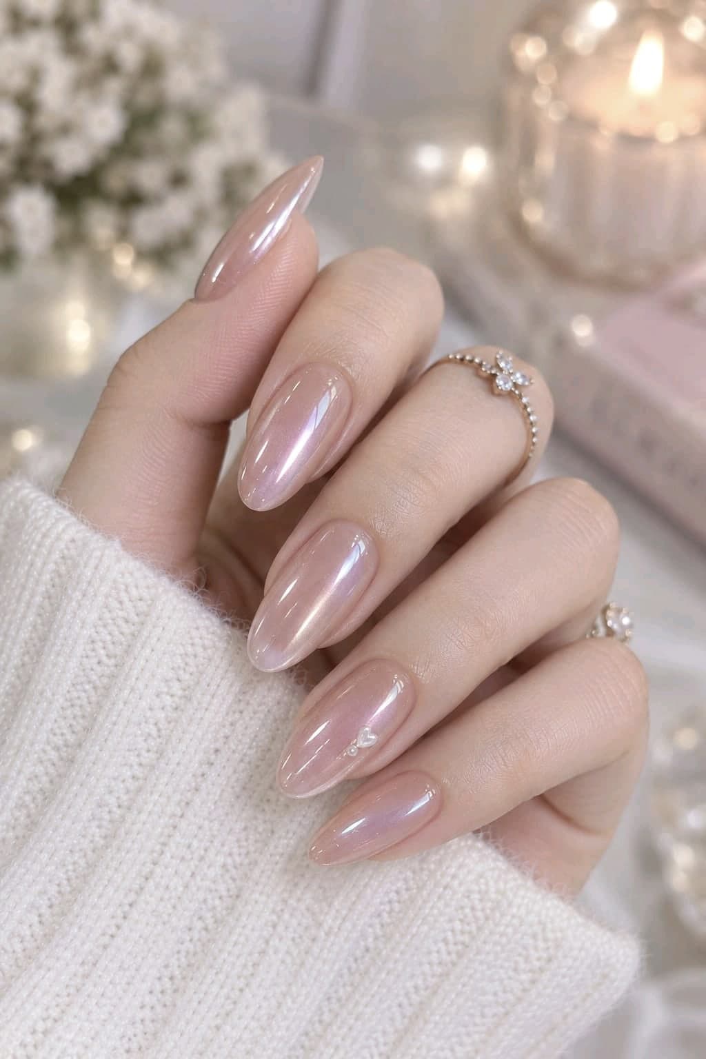 Soft pink glazed donut almond nails with pearly chrome shine and a tiny heart charm