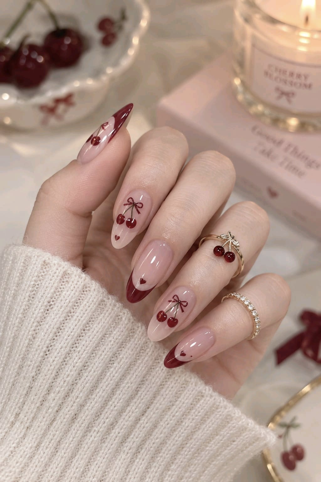Nude almond nails with hand-painted cherries, tiny burgundy bows and deep burgundy French tips