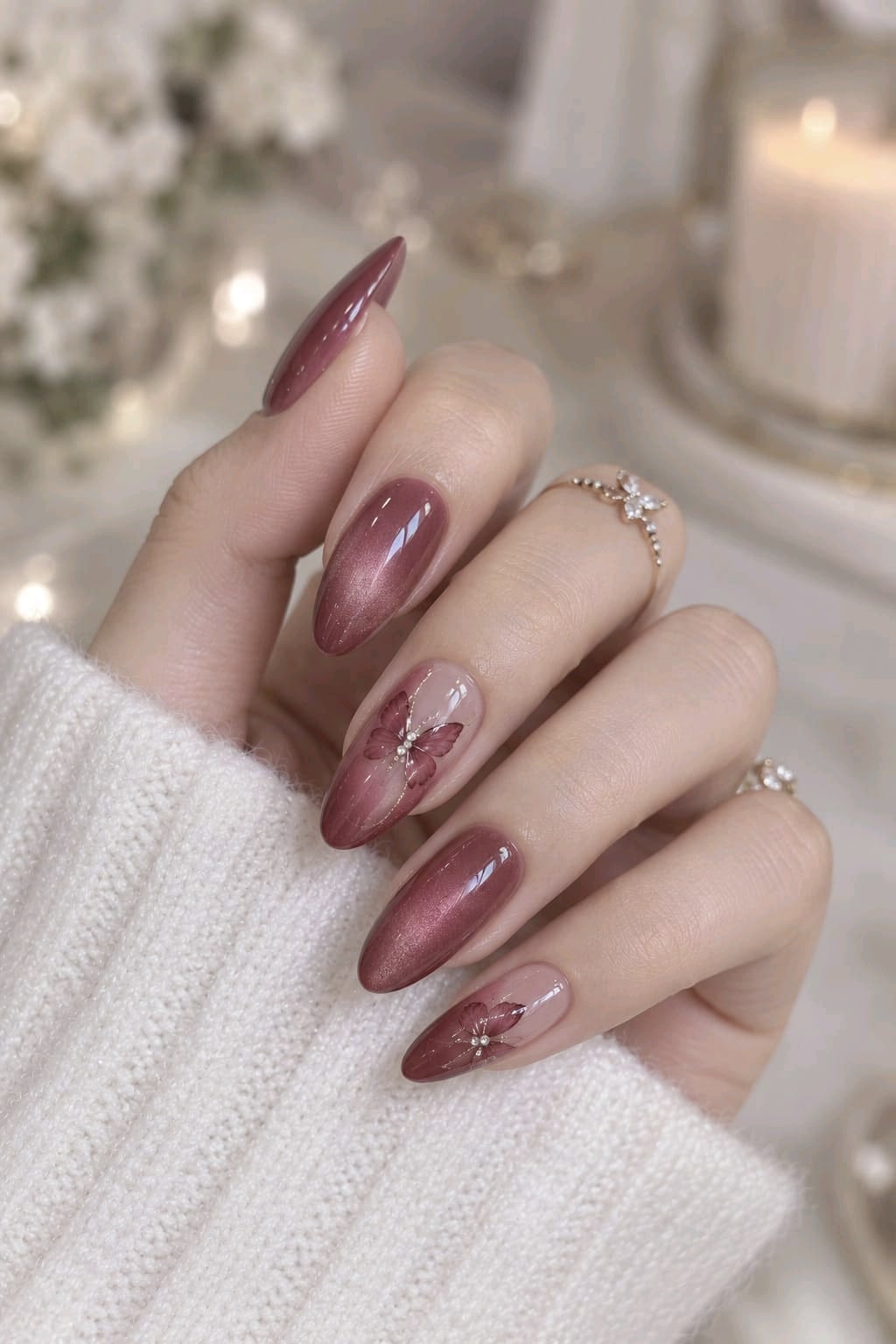Dusty rose cat eye almond nails with velvet shimmer and burgundy butterfly accents on nude nails